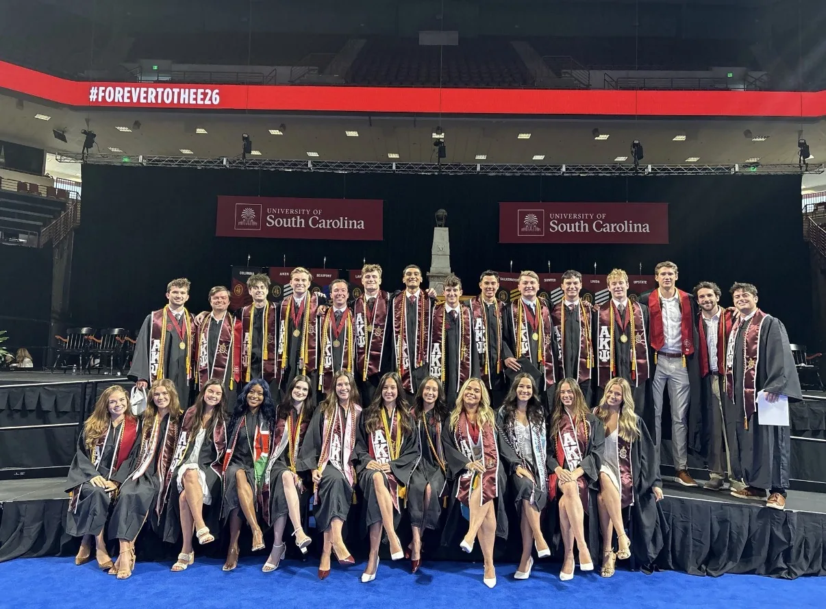Graduating Alpha Kappa Psi brothers on stage at USC commencement