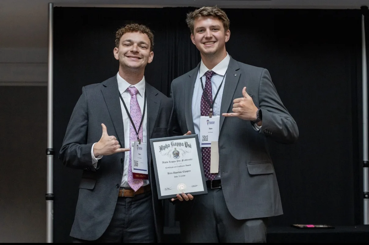 Beta Upsilon brothers accepting the Alpha Kappa Psi Certificate of Excellence