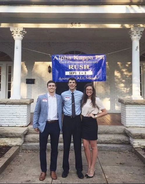 Brothers in business casual attire in front of the AKPSI house